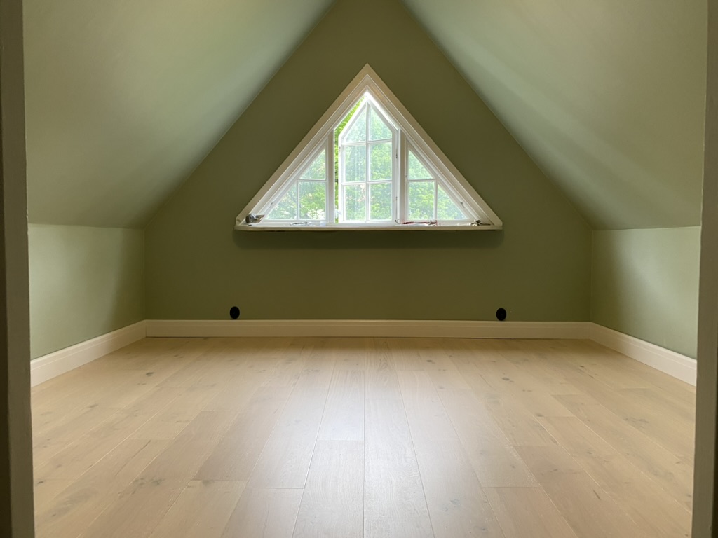 Vindsrum med gröna väggar och nylagt trägolv