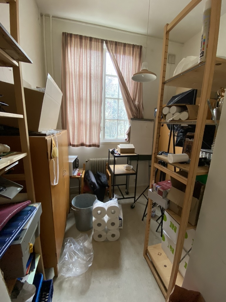 Belamrat litet rum med hyllor och daterade gardiner