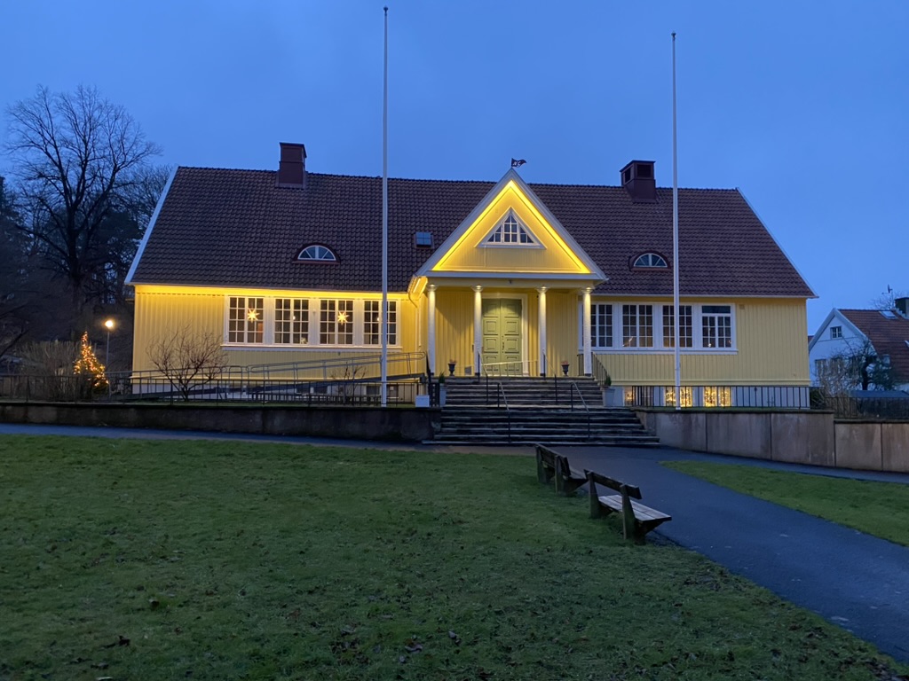 Villan upplyst i kvällsljus, varm belysning mot fasaden