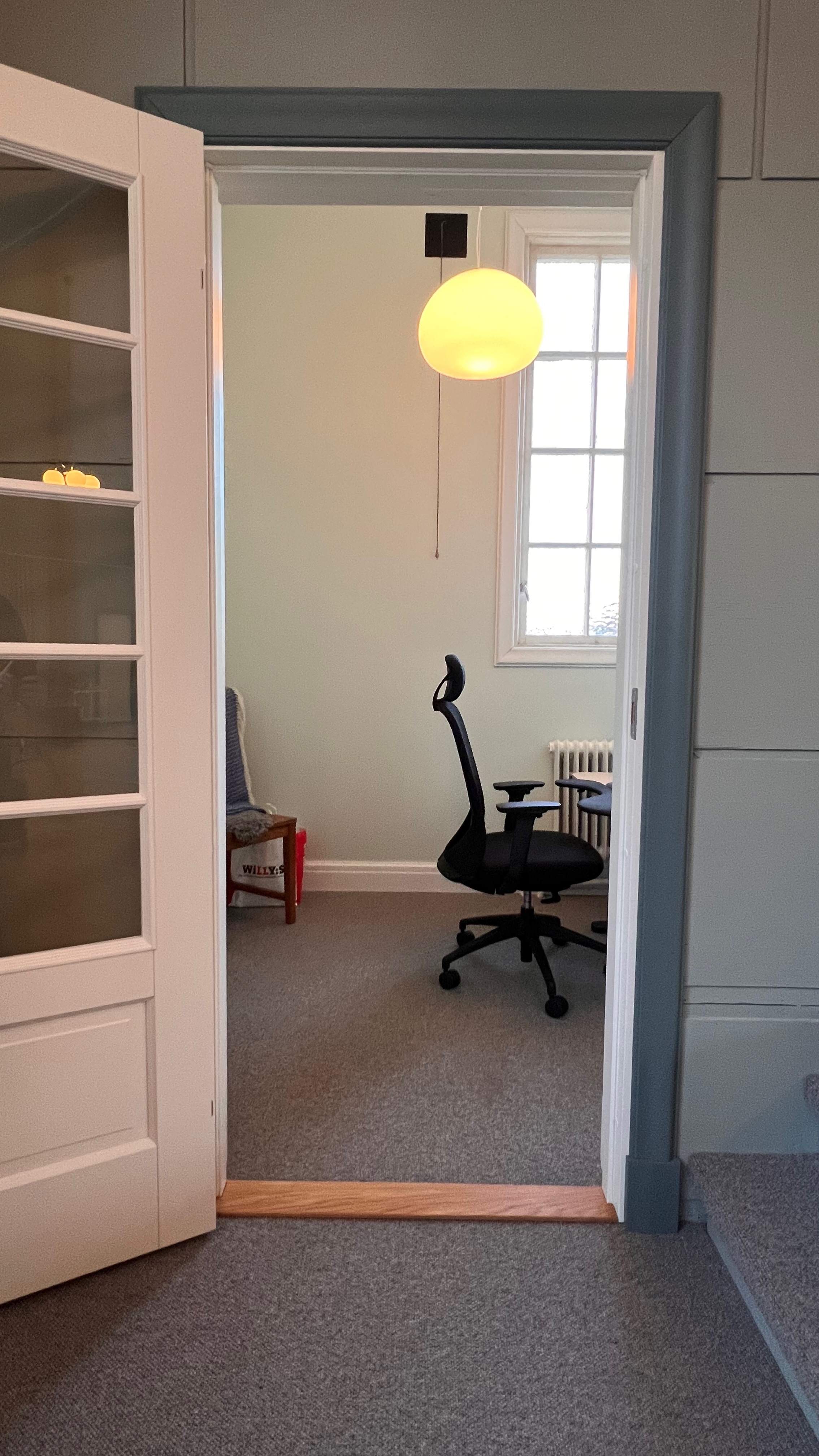 Litet kontorsrum med skrivbord och pendellampa