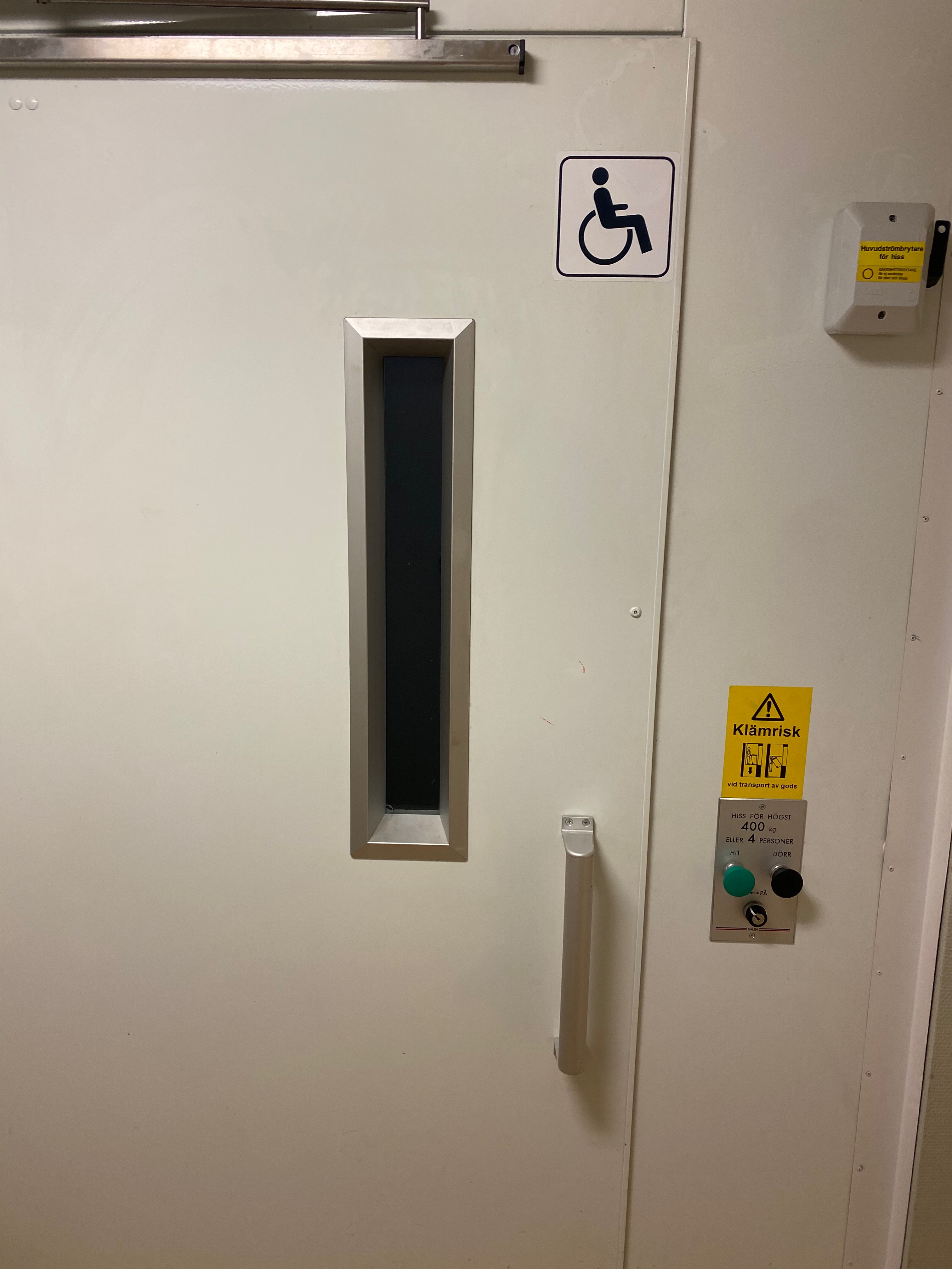 Hissdörr med handikappmarkering och klämrisk-skylt