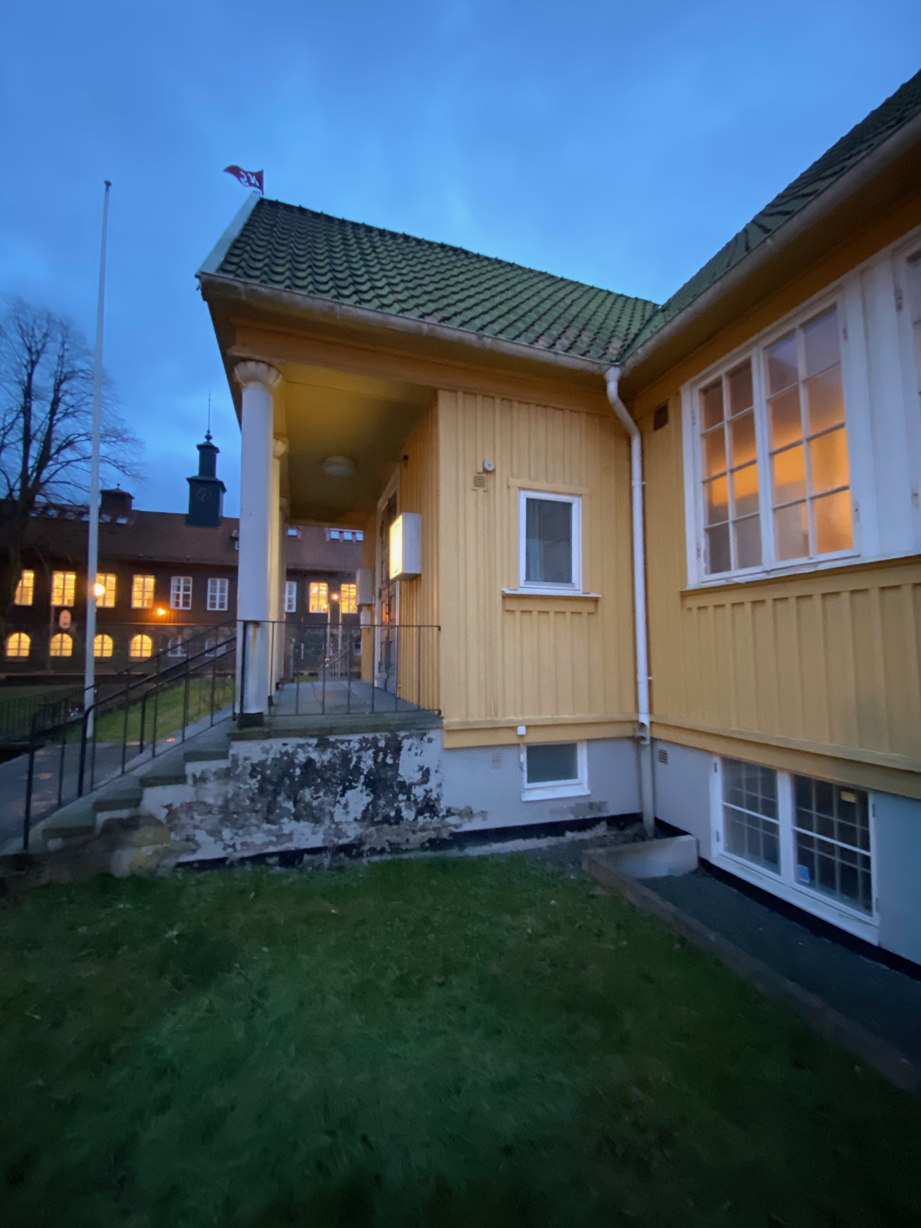 Entrén med vittrade stentrappor och flaggstång