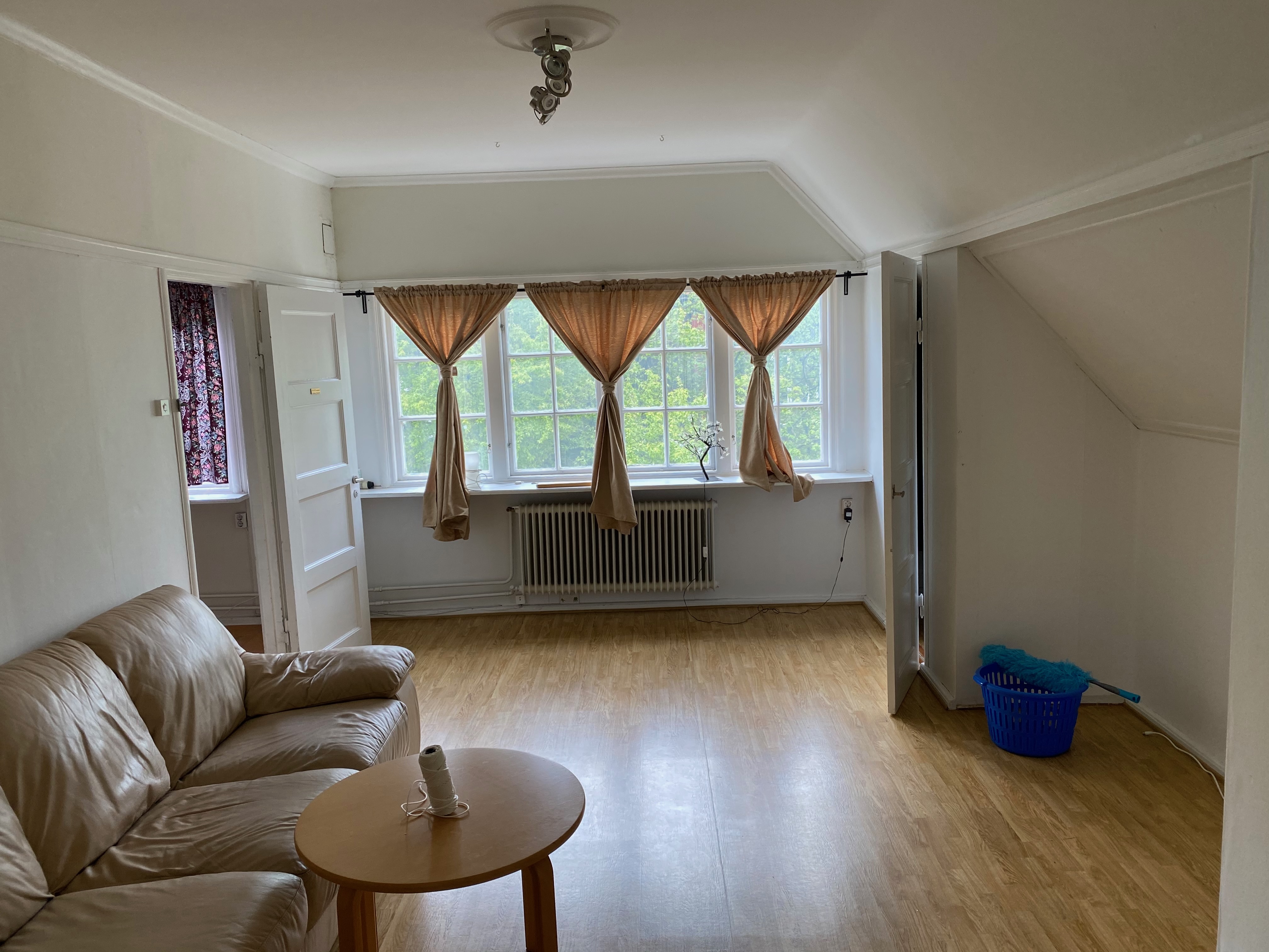 Rum med gammal soffa och enkla gardiner