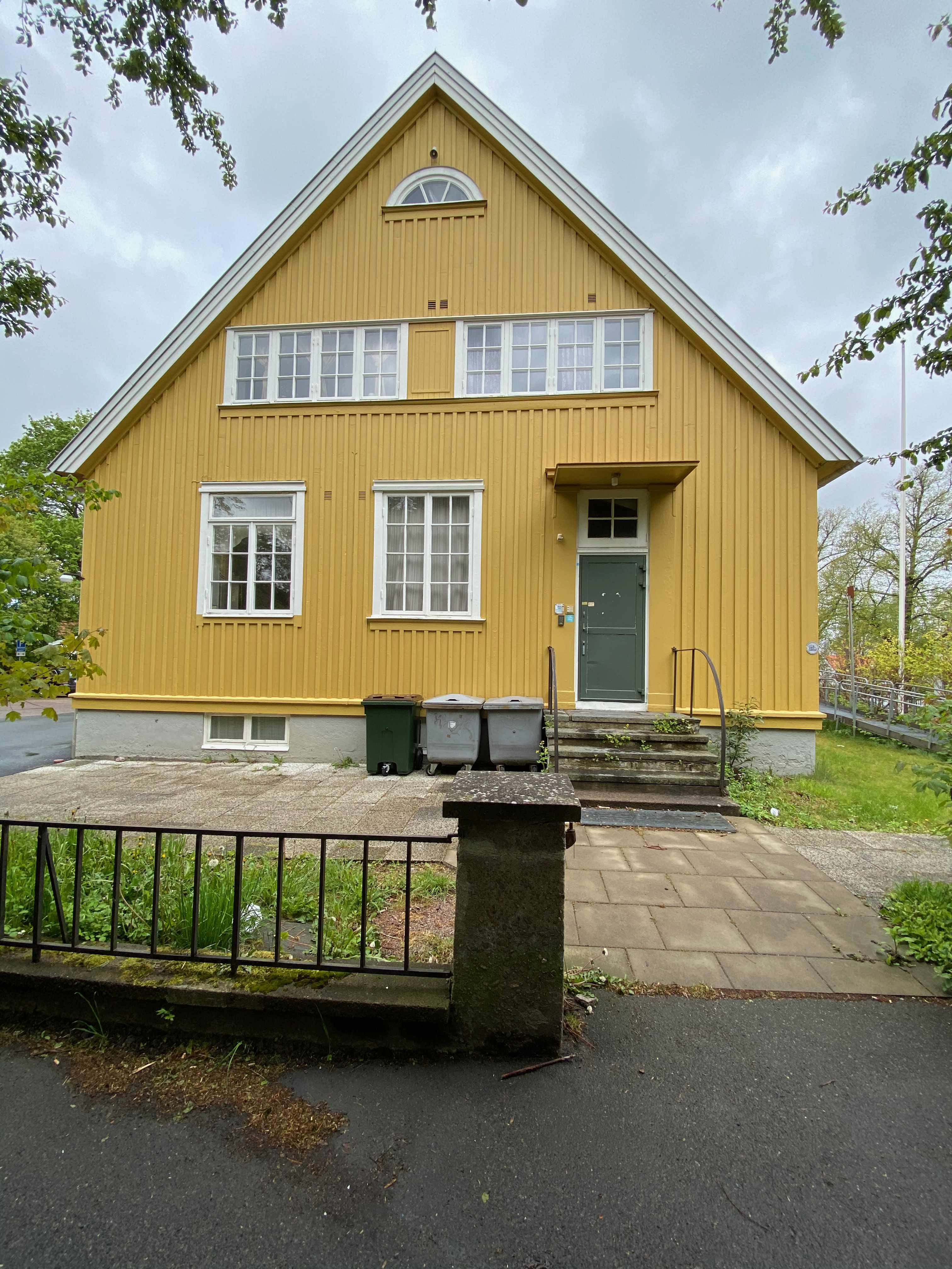 Baksidan med grön dörr och soptunnor