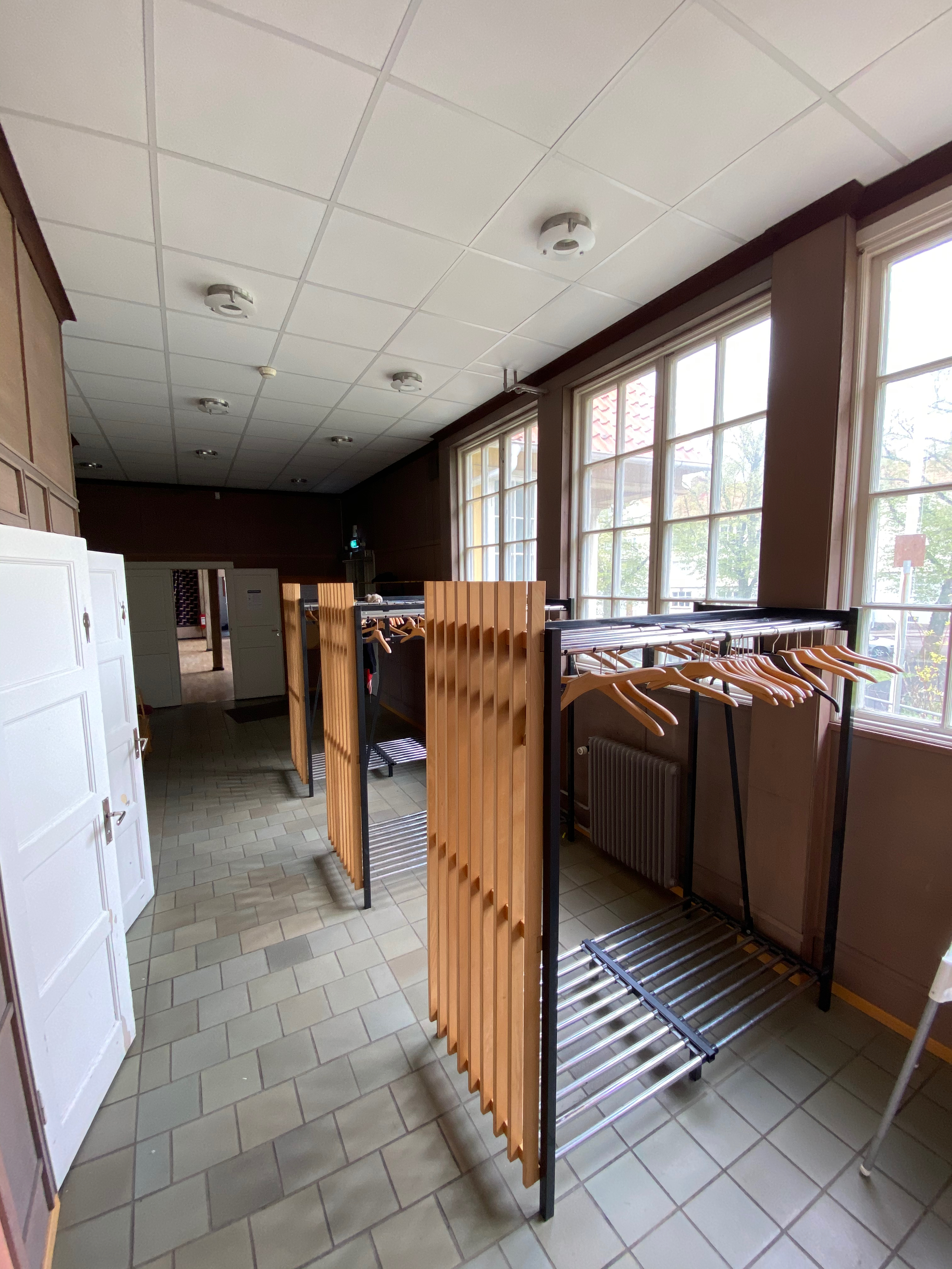 Kapprum med trähängare och bruna panelväggar