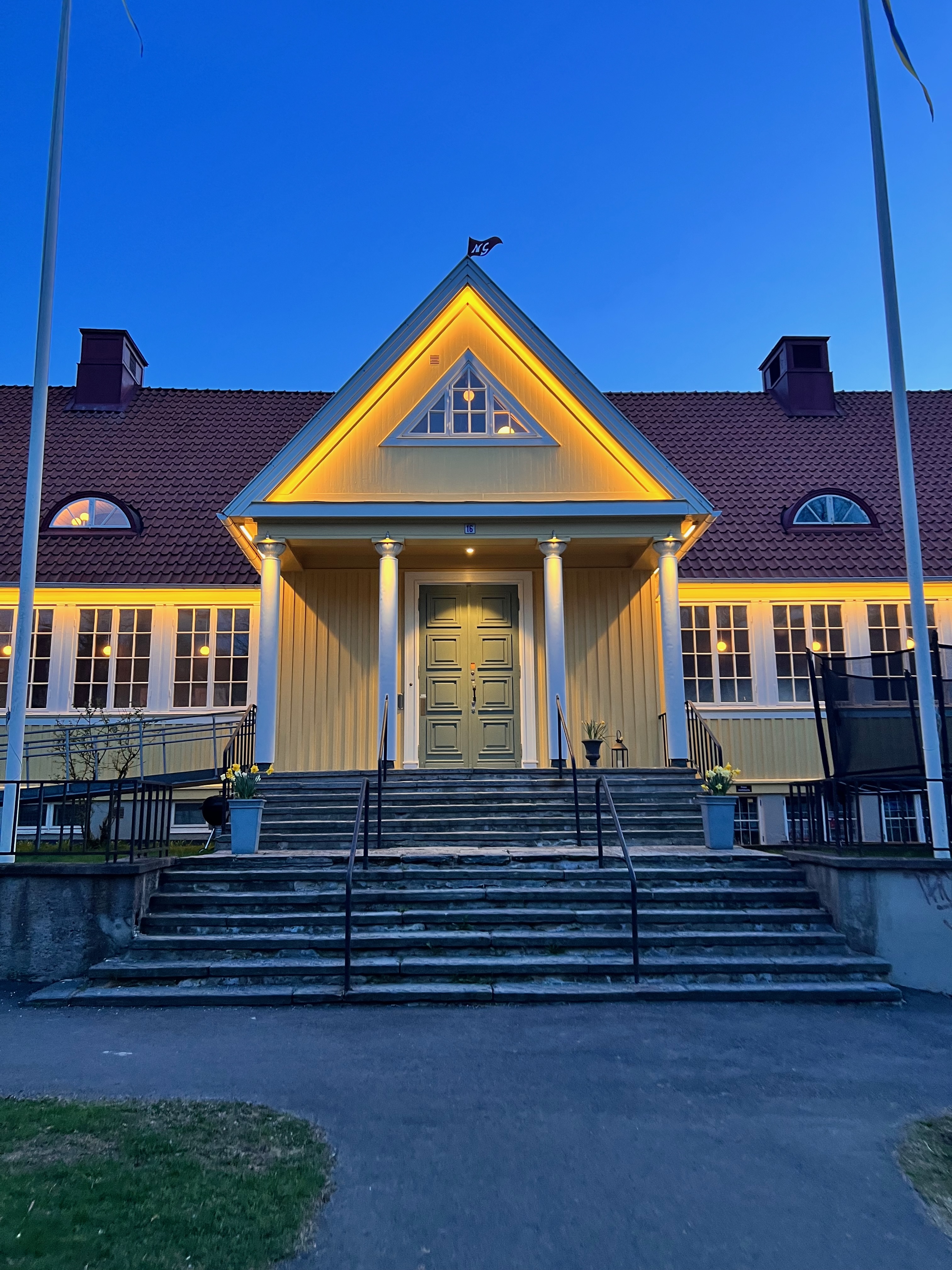 Entrén i kvällsljus med upplysta pelare och trappa