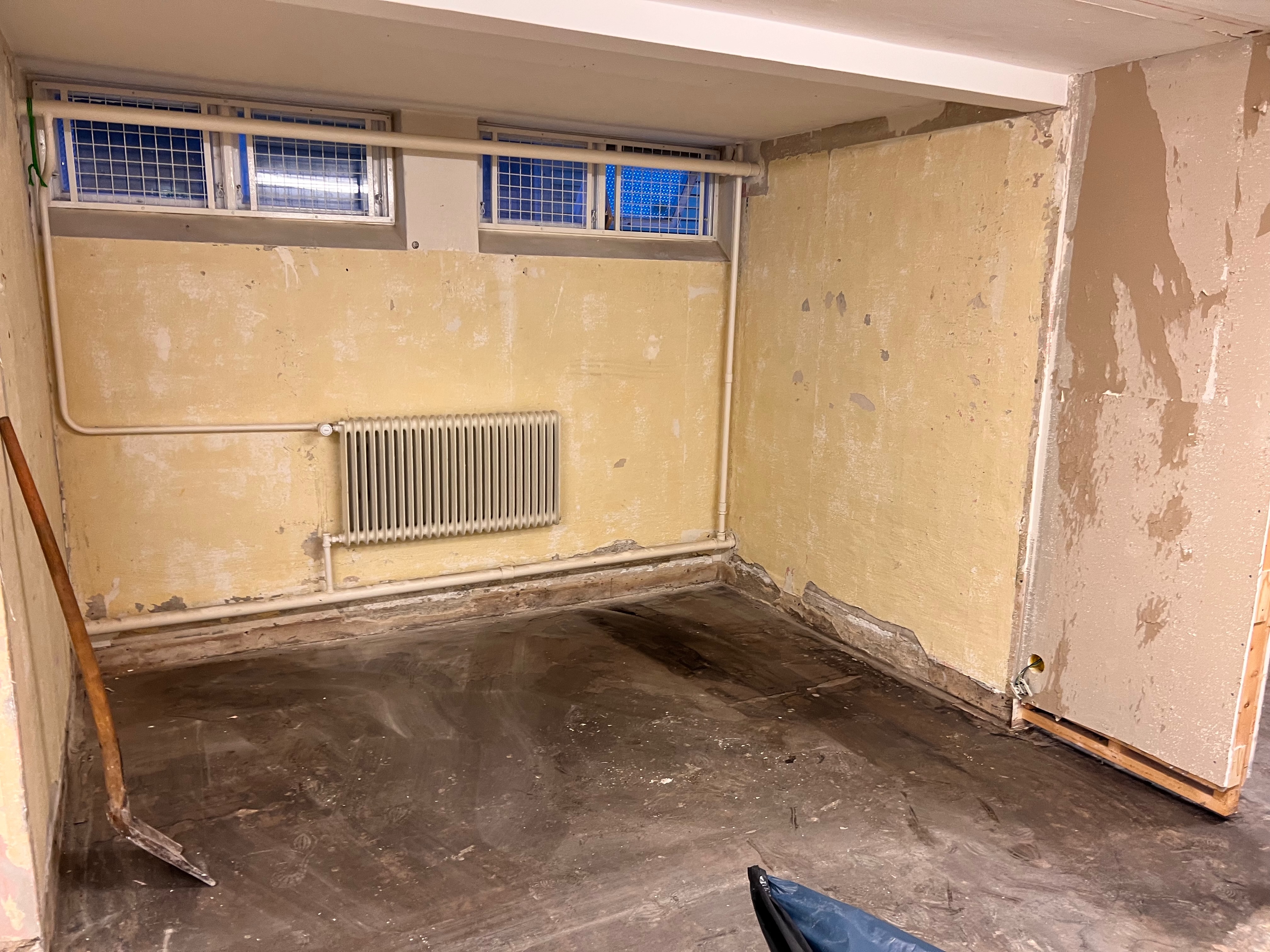 Källarrum med flagnad gul färg och betong