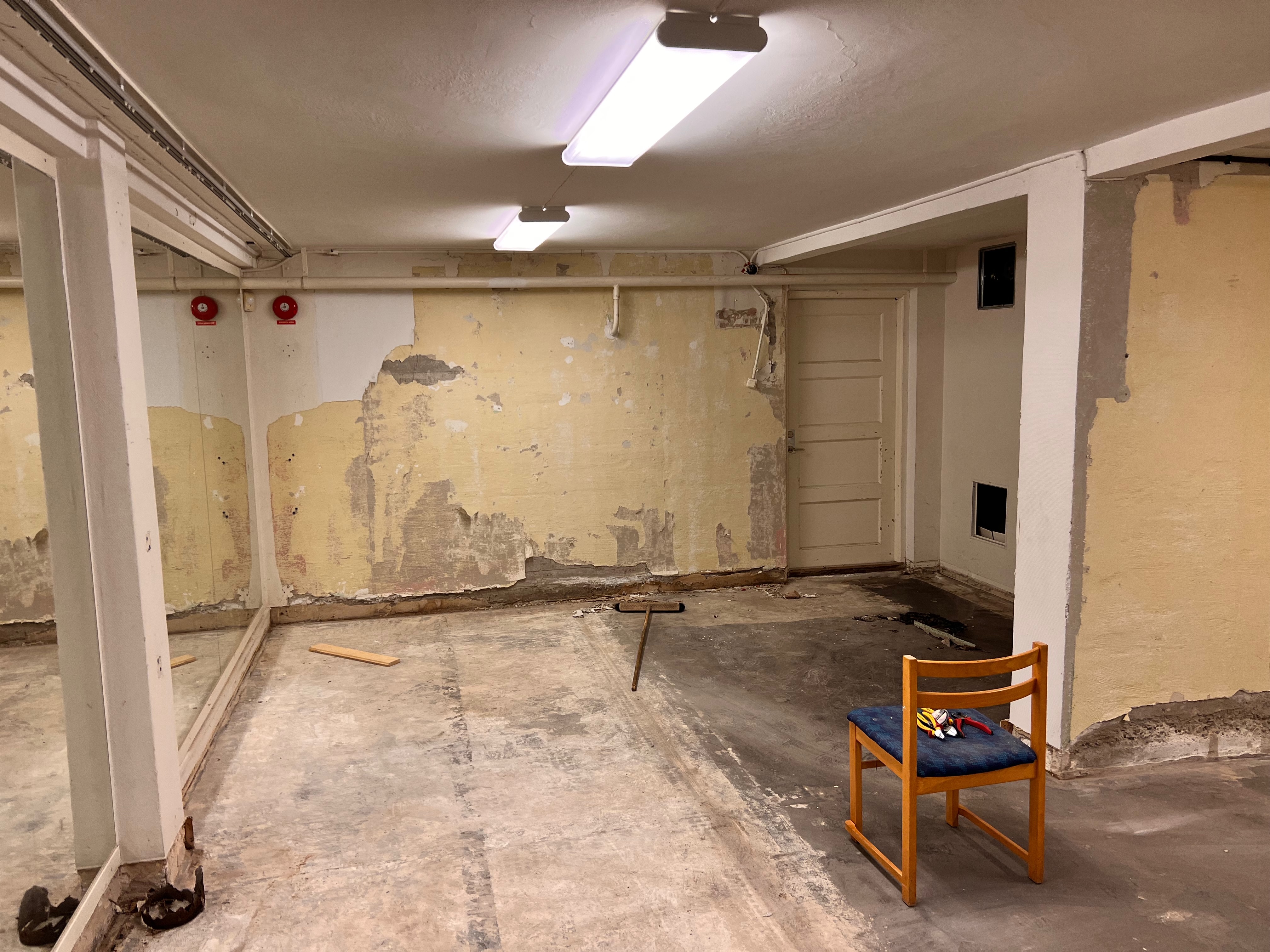 Källarrum med rivna väggar och gammal brandvarnare