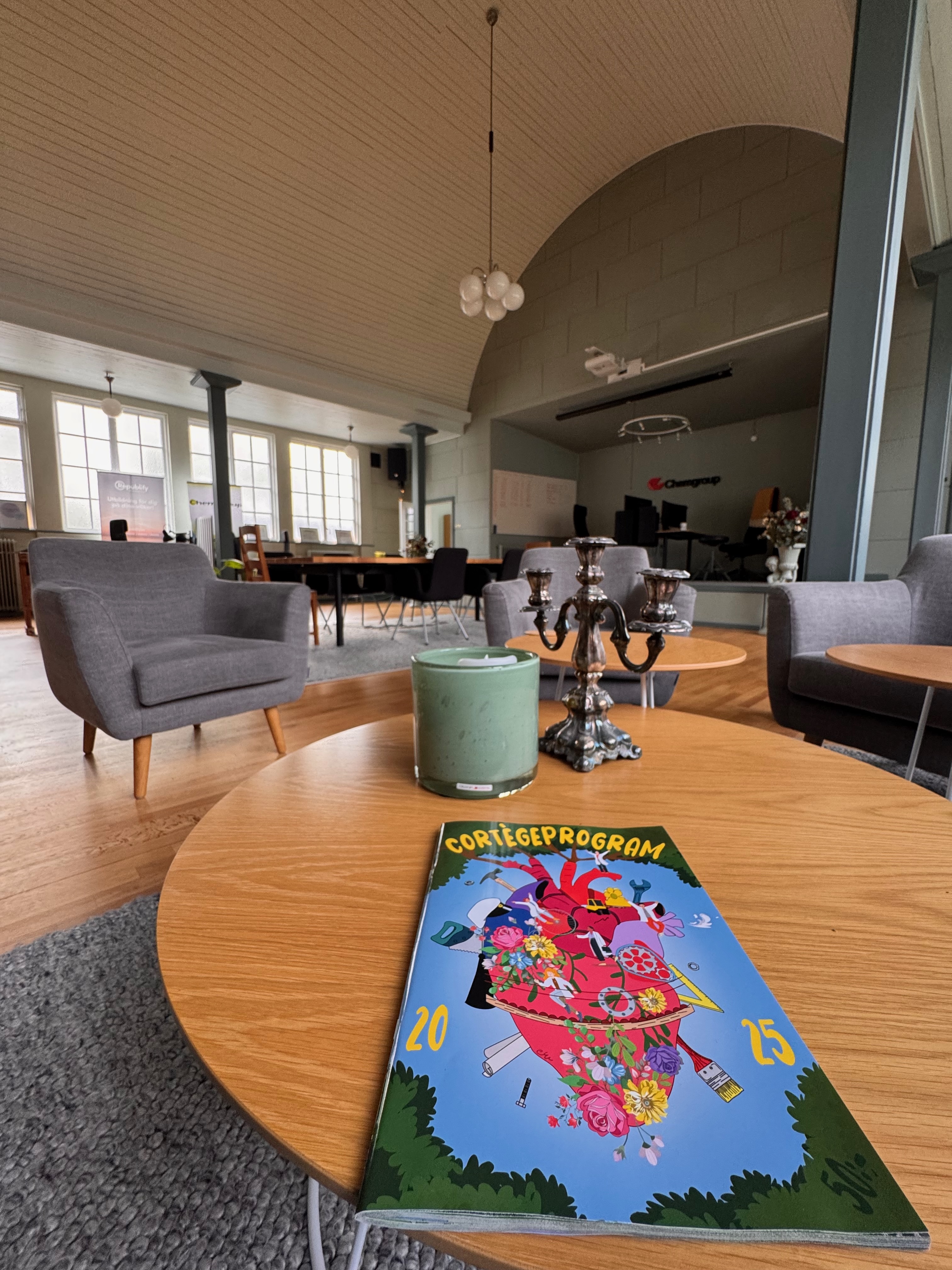 Lounge med fåtöljer, kandelaber och tidning på soffbordet