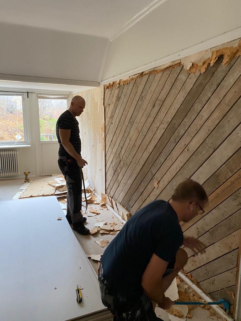 Arbetare river tapet och blottlägger gamla träplankor